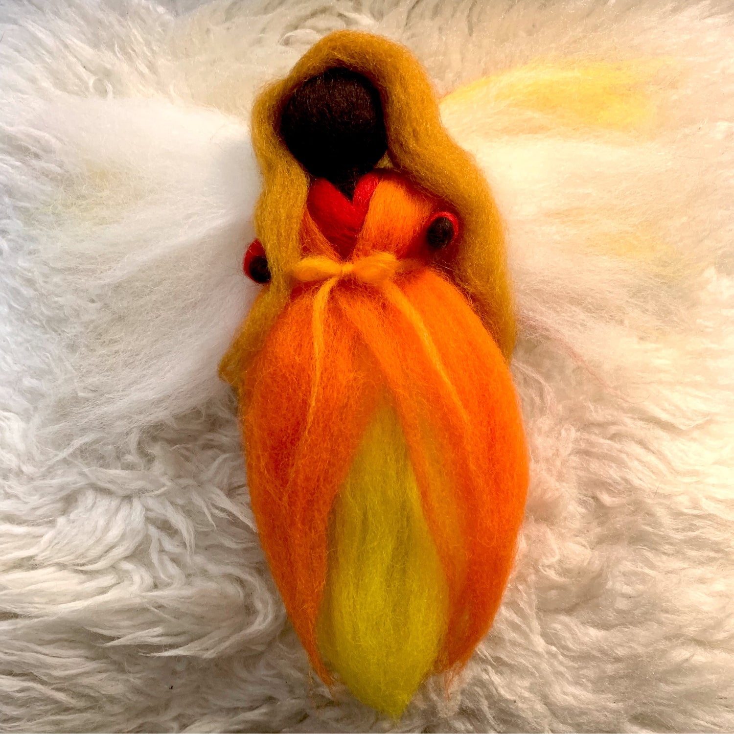 wool fairy made with orange, red, yellow, and white wool.